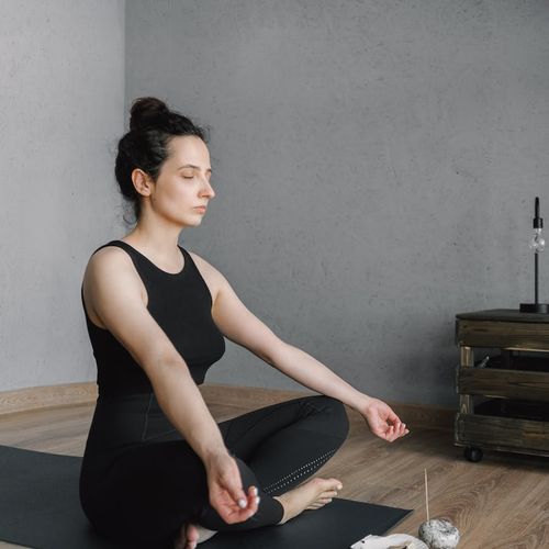 A calm person meditating in a bright, sunlit room.