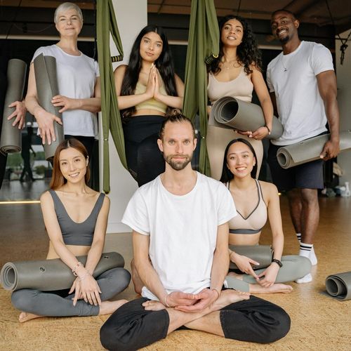 Diverse group of people smiling and preparing for a yoga class.