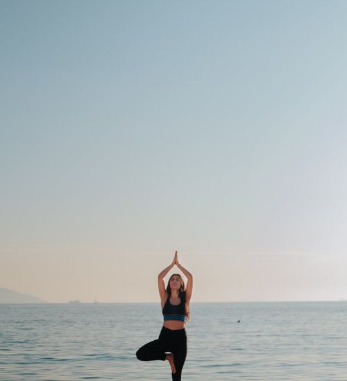 Woman practicing a peaceful yoga pose at sunrise.